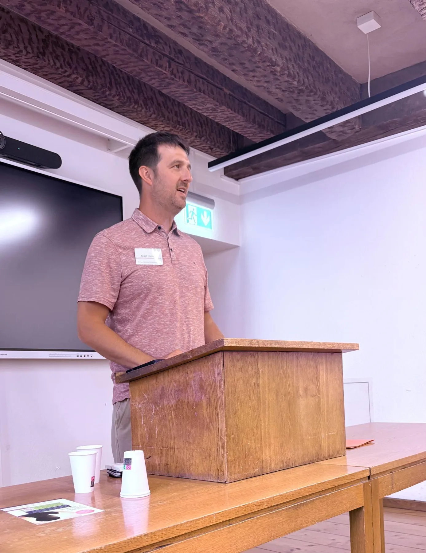 Dr. Brant Himes speaking at a podium at the 2026 European Neo-Calvinism Conference, University of Basel